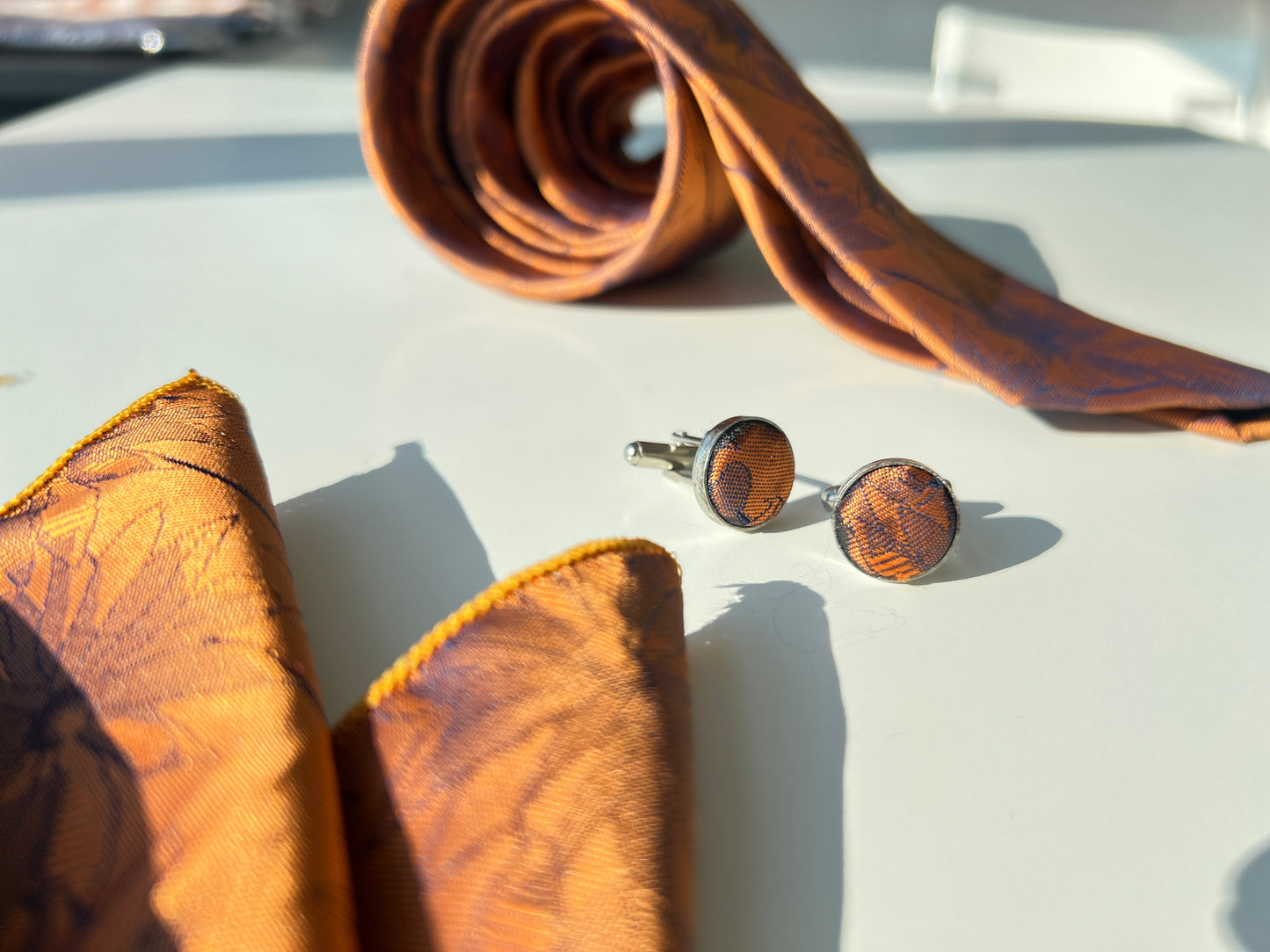 Close-up of bronze floral tie fabric and cufflinks set