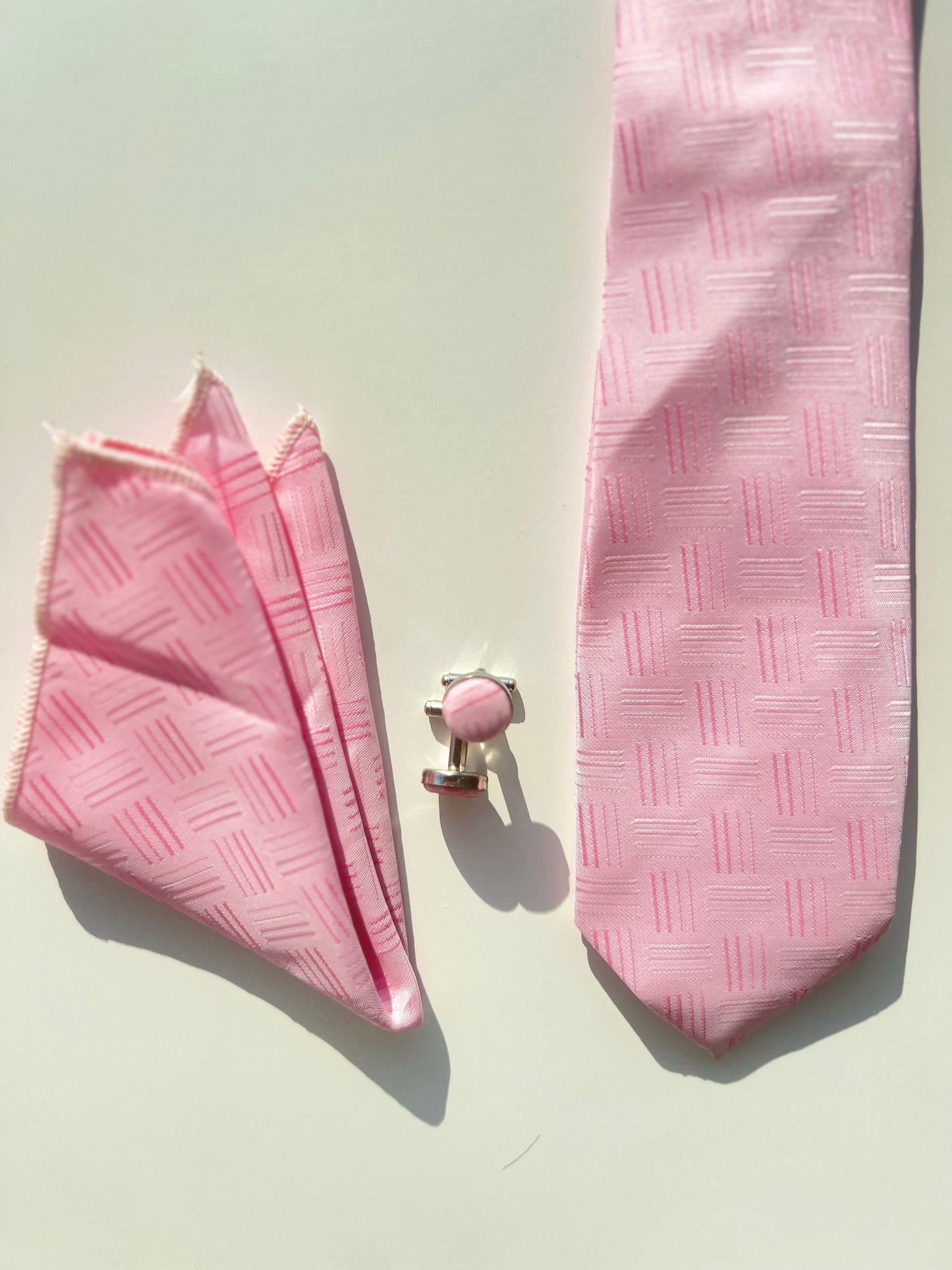 Charming pink textured silk tie set with matching cufflinks and pocket square on a white background