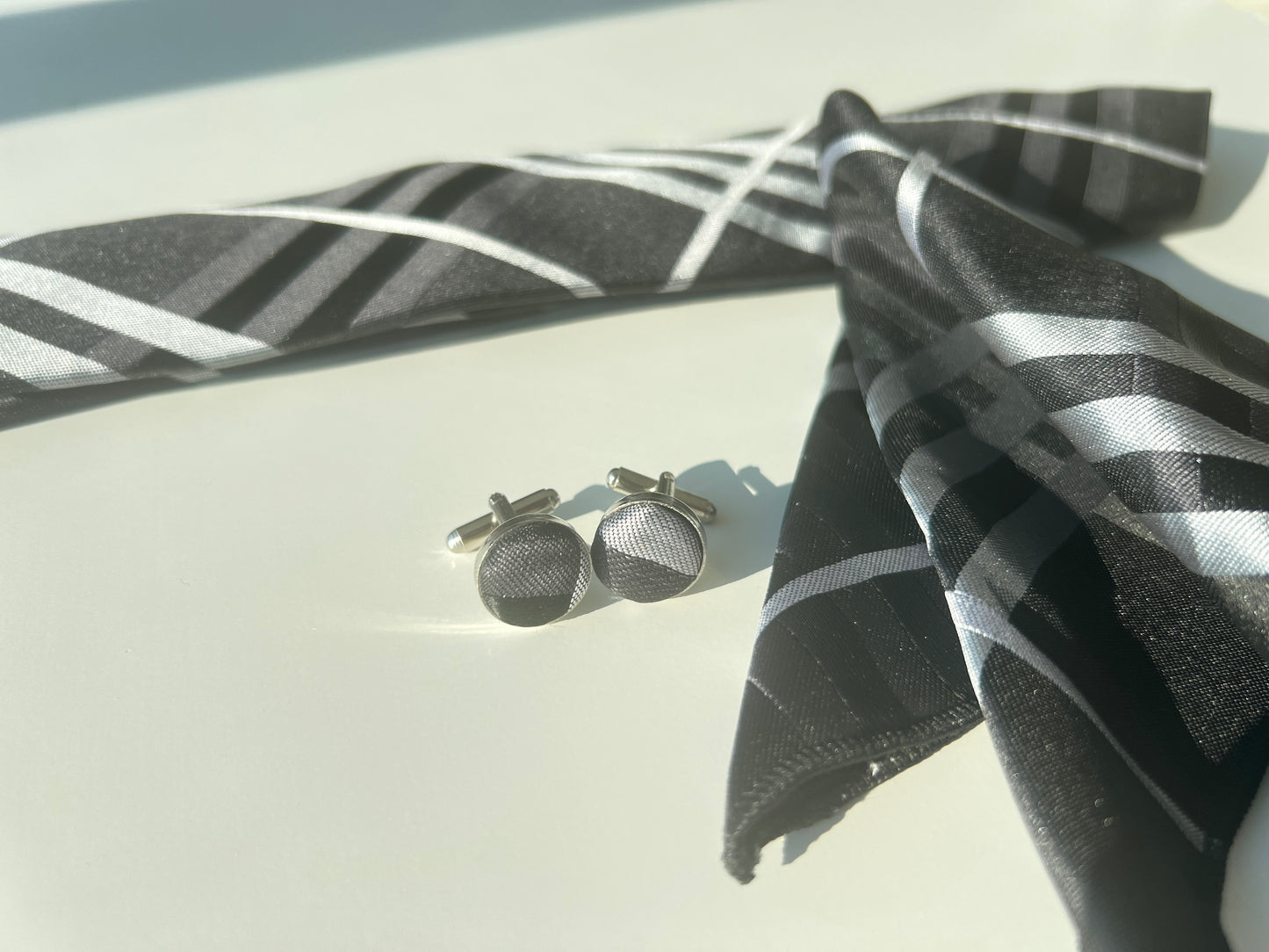 Close-up view of the tie's geometric pattern and the textured cufflinks.