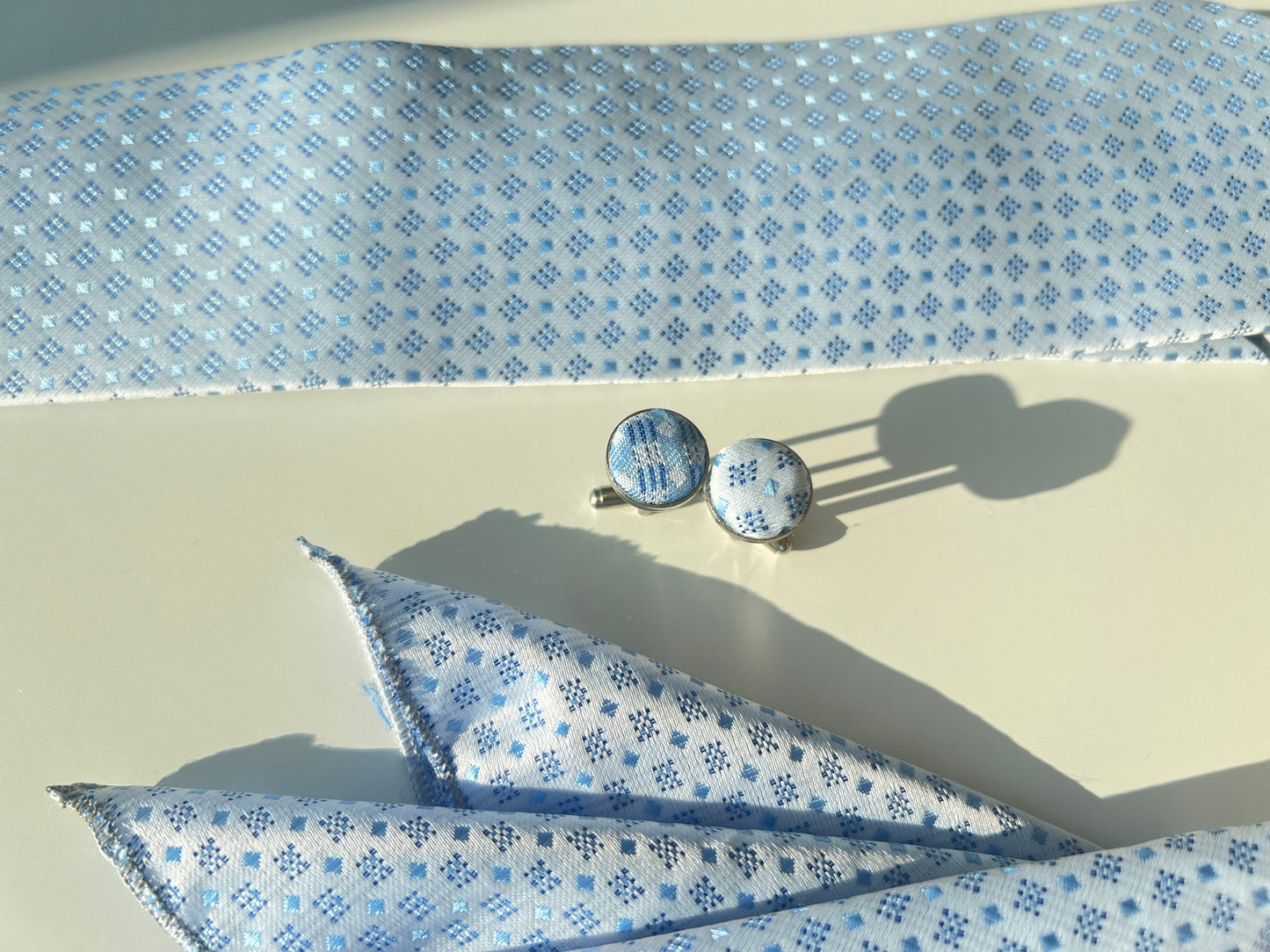 Detailed view of the silk tie's snowflake pattern and matching cufflinks.