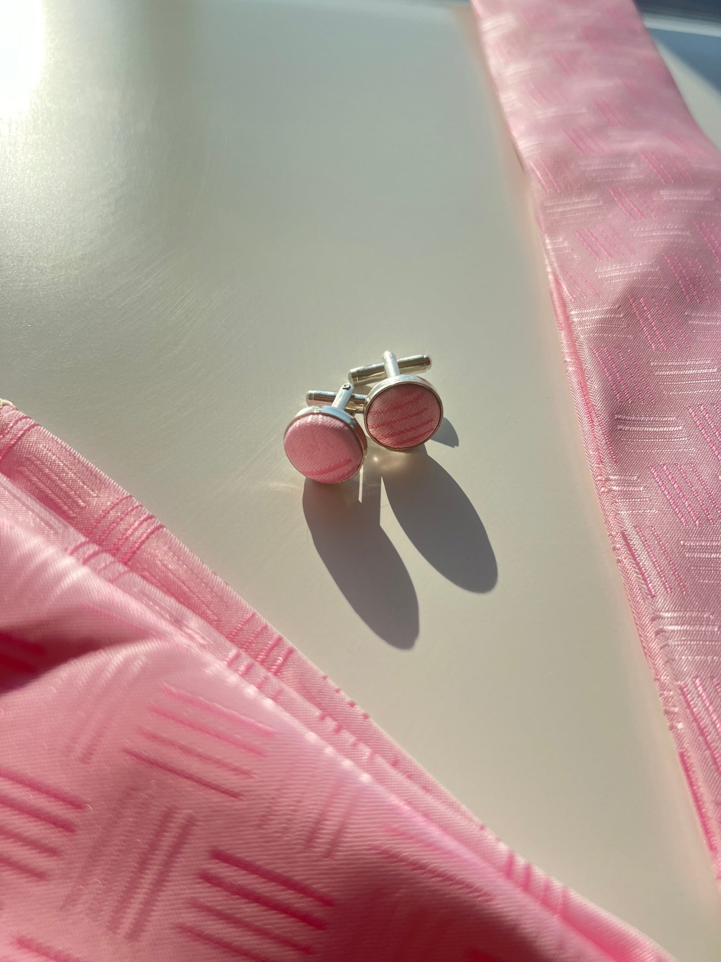 Close-up of the pink silk tie's textured pattern and matching cufflinks