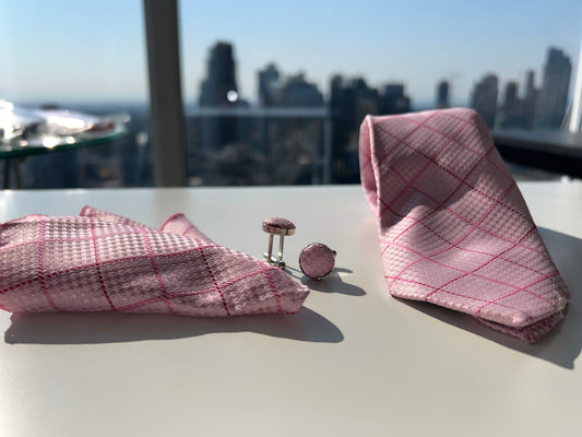 Elegant pink and white diamond pattern tie with matching pocket square and cufflinks laid out on a light surface.