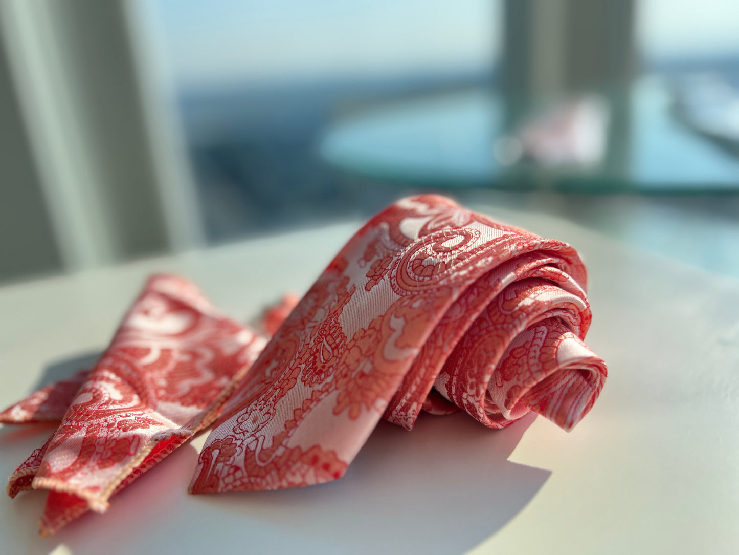 Elegant red silk tie set displayed, highlighting the lush paisley design and matching accessories