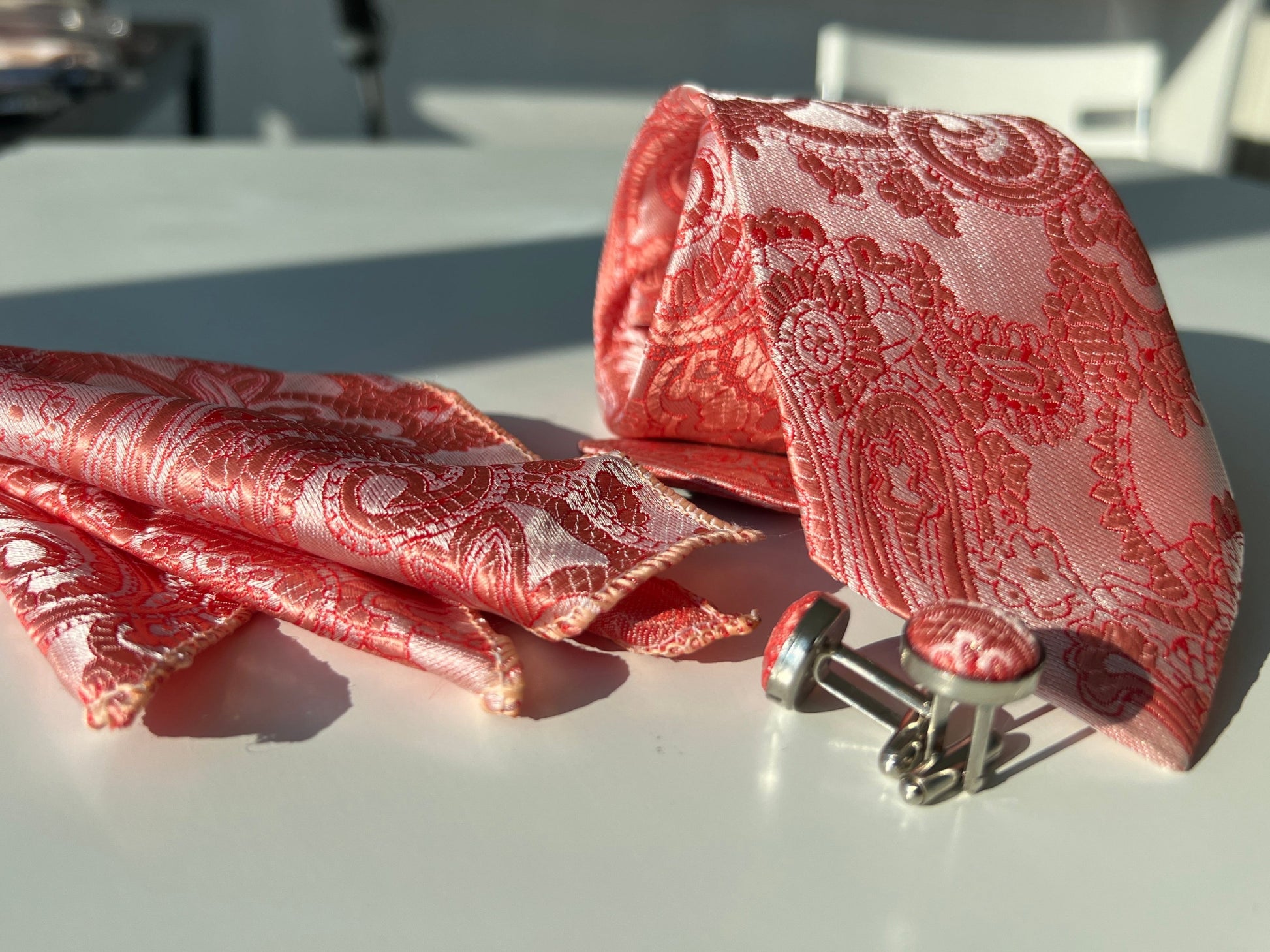 Elegant red silk tie set displayed, highlighting the lush paisley design and matching accessories